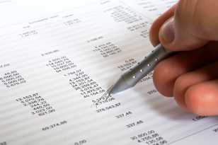 photo of a spreadsheet with mortgage costs breakdown and a hand holding a pen circling numbers on the spreadsheet